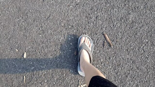 The Video or Footage of A Pair of Feet Wearing Sandals Walking Along An Asphalt Road Paved With Decorative Concrete Blocks Was Recorded From Above. Road Materials Coarse Texture Housing in Indonesia
