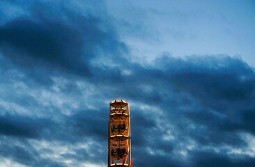 Emporragendes Riesenrad vor Himmel mit dunklem Wolkengebilde in Stadt auf Weihnachtsmarkt am Abend...