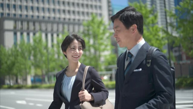 ビジネス街を歩く50代男性会社員と30代女性会社員