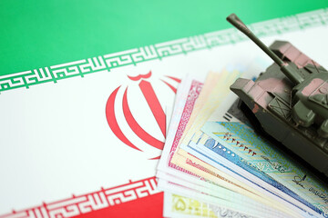 Iranian army toy tank drive on iranian bills of rial currency on flag of Islamic Republic of Iran...