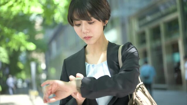 腕時計を確認する30代女性会社員