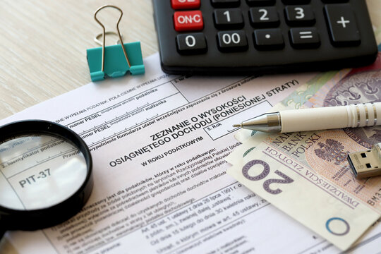 Declaration of the amount of earned income or incurred loss, PIT-37 tax forms on accountant table with pen and polish zloty money bills close up