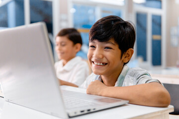 Portrait school cheerful boy using digital device in school classroom.