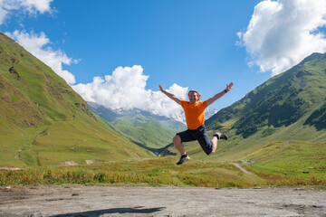 Fototapeta premium Peak Aerial: Man Leaping through the Air in an Orange T-Shirt