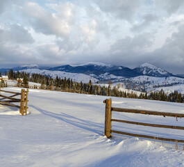 Morning countryside hills, groves and farmlands in winter remote alpine mountain village