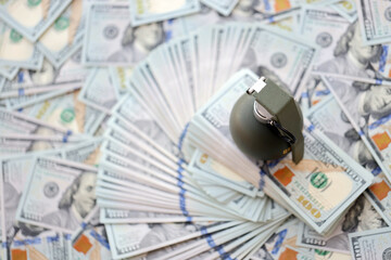 Grenade with a check against the background of huge amount of american dollar bills close up