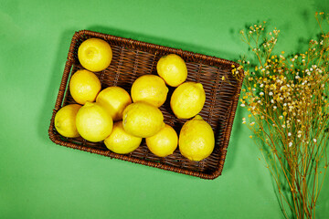 fresh lemon in esparto halfah basket with gypsophila flowers on green background