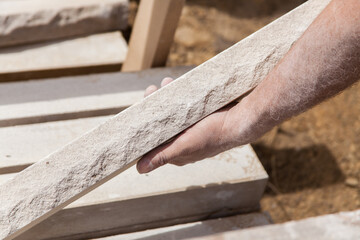 Hand holding a piece of natural stone veneer. Stone mason.