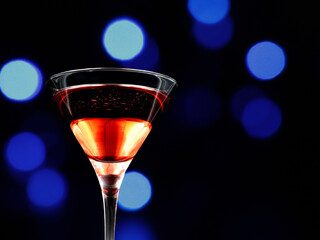 Festive drink in a martini glass in front of a bokeh background.
Red aperitif drink for festive...