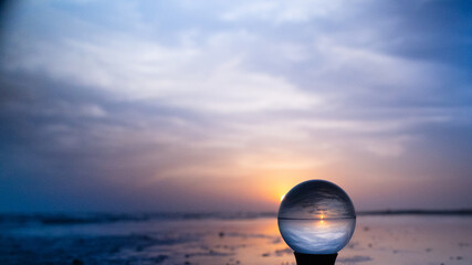 Crystal lens ball on a stand at the beach at sunrise in blues and violets. Glass photography ball...