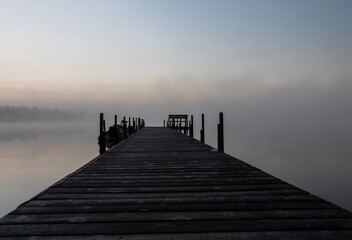 Early morning fog at the dock with a fishing boat and bench on Lake Vermilion in northern Minnesota
