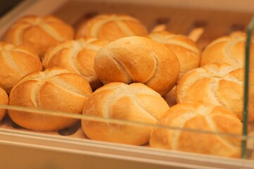 A Tempting Stack of Freshly Baked Bread Rolls on a Wooden shelf, Bathed in Warm Light from Above – Front View
