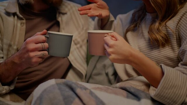 Unrecognizable couple having discussion and holding cups