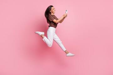 Full body length photo of young active blogging lady running in air with phone sending video message isolated on pink color background - obrazy, fototapety, plakaty