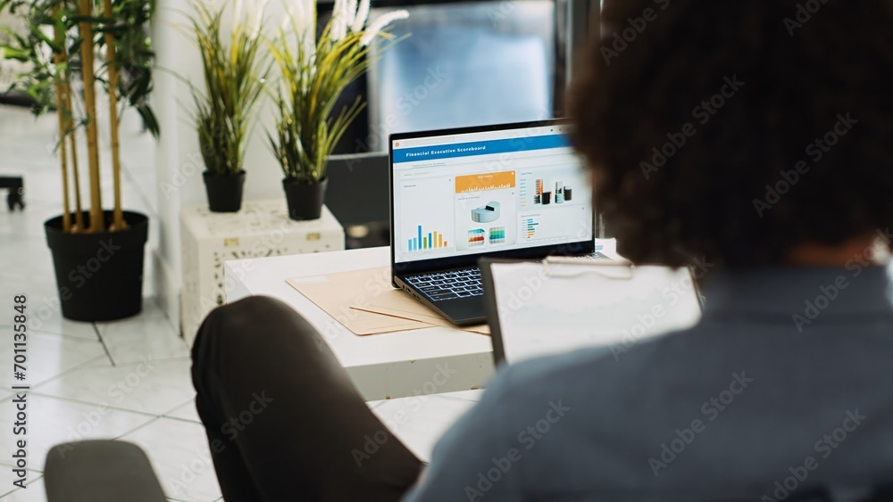 Poster middle eastern man studying trends and statistics to create annual report, using archives analytics.