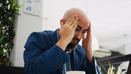 Burnout in coworking space. Businessman being tired and having migraine at work, trying to develop...
