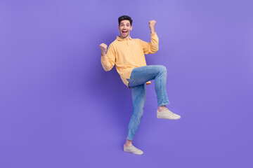 Fototapeta na wymiar Full size photo of attractive young man raise fists celebrate big sales dressed stylish yellow clothes isolated on purple color background