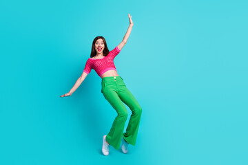 Fototapeta na wymiar Full length photo of cute careless woman dressed pink top green retro pants stand on tiptoes falling isolated on blue color background