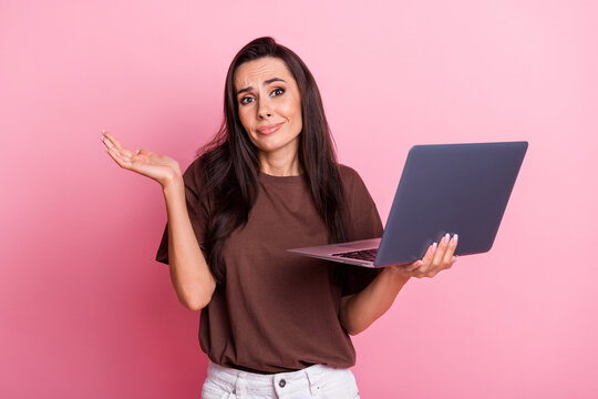Photo of young funny woman working indifferent shrug shoulders ignoring boss messages using laptop isolated on pink color background
