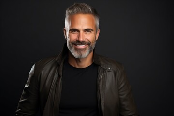 Portrait of handsome mature man in leather jacket on dark background.