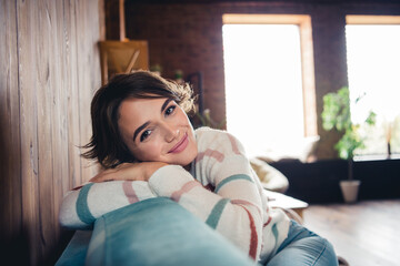 Photo of satisfied adorable girl sitting comfy sofa have good mood pastime morning chill apartment...