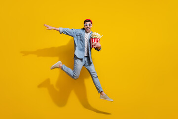 Fototapeta na wymiar Full length photo of cool carefree man dressed jeans shirt eating pop corn watching vr movie empty space isolated yellow color background