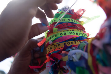Tourist hands tying souvenir ribbon on the iron railing of the Senhor do Bonfim church in the city of Salvador, Bahia.