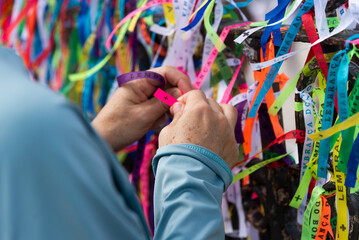 Catholics and tourists are seen tying a souvenir ribbon on the iron railing of the Senhor do Bonfim...