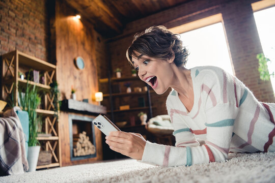 Profile photo of impressed cheerful lady open mouth use smart phone typing texting daylight house indoors
