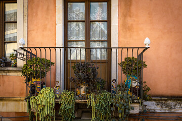 Fototapeta na wymiar Decorated balcony with heads and succulents in Taormina on a rock terrace on the slope of Monte Tauro, Sicily, Italy