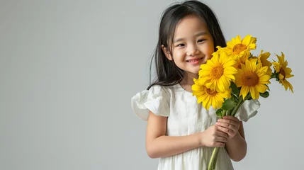 Foto auf Acrylglas Cute smiling child girl holding bouquet of spring flowers blooming yellow sunflowers isolated on beige background. Little toddler girl gives a bouquet to mom. Copy space for text. © Jasper W