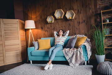 Full body photo of creative gorgeous lady sit cozy couch hands behind head look up contemplate apartment inside