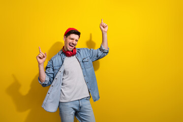 Photo of excited funky man dressed jeans shirt dancing pointing two fingers empty space isolated yellow color background