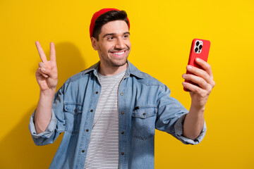 Photo of funky cool man dressed jeans shirt showing v-sing recording video vlog modern gadget isolated yellow color background