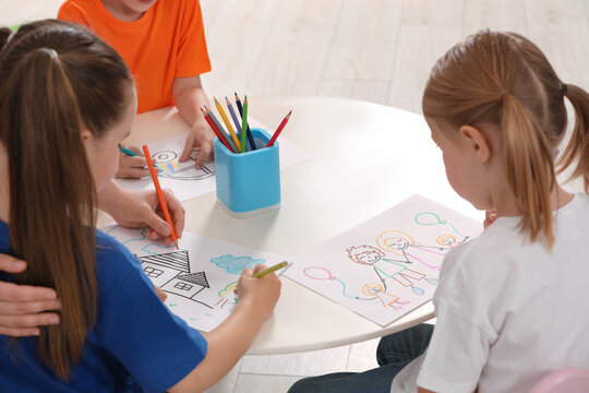 Cute little children drawing pictures at desk in kindergarten. Playtime activities