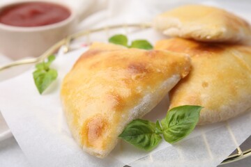 Delicious samosas and basil on white table, closeup