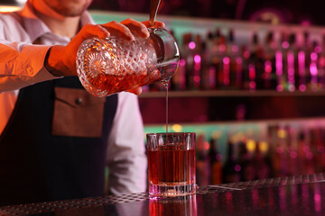 Bartender making fresh alcoholic cocktail at counter in bar, closeup. Space for text