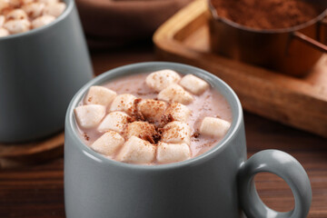 Cups of aromatic hot chocolate with marshmallows and cocoa powder on table, closeup