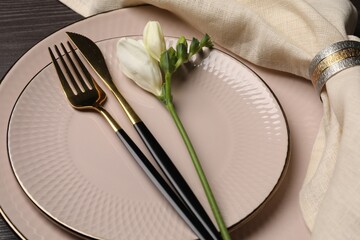 Stylish table setting. Plates, cutlery, napkin and floral decor on background, closeup