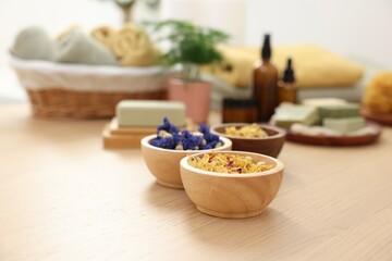 Bowls of dry flowers on light wooden table. Spa therapy