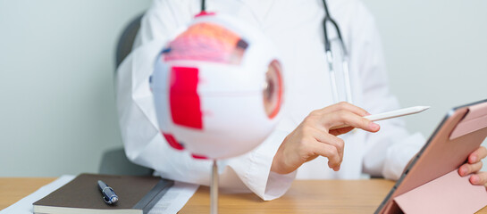 Doctor with human Eye anatomy model with magnifying glass. Eye disease, Refractive Errors, Age...