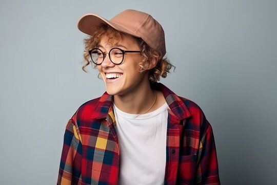Portrait of a cheerful young hipster guy in glasses and a cap