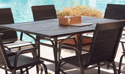 wooden chair and table place nearby the pool.