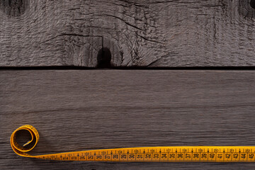 Yellow Measuring Tape on Rustic and Old Wooden Background.