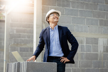 An Asia man engineer is working manager on a project under construction for a house.A handsome man with black skin was smiling confidently. Wear personal protective equipment,PPE.