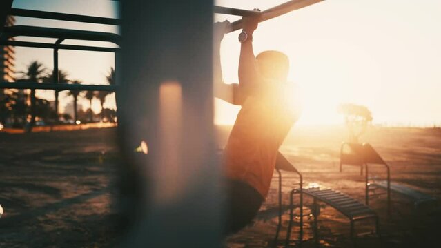 Sunrise, silhouette and man in park for fitness, pull up on jungle bars for workout and muscle training outdoor. Sunshine, lens flare and exercise, strong athlete with bodybuilding and power