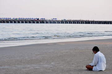 alone young woman young girl sitting on the beach Morning atmosphere, soft sunlight, ideas for relaxing on vacation. Release emotions of loneliness, brooding, heartbreak, escaping from society.