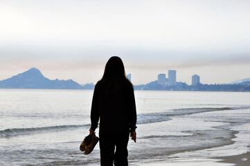 Alonewoman girl standing on the beach girl walking towards the sea In the morning atmosphere, soft...