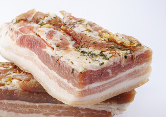 Appetizing salty lard with layers of meat with garlic and herbs. Two pieces of salted lard on a white background.