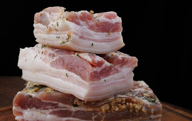 Appetizing salty lard with layers of meat with garlic and herbs. Delicious lard on a wooden cutting...